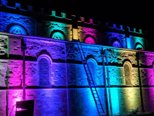 Historic building facade lit in purple, blue and pink